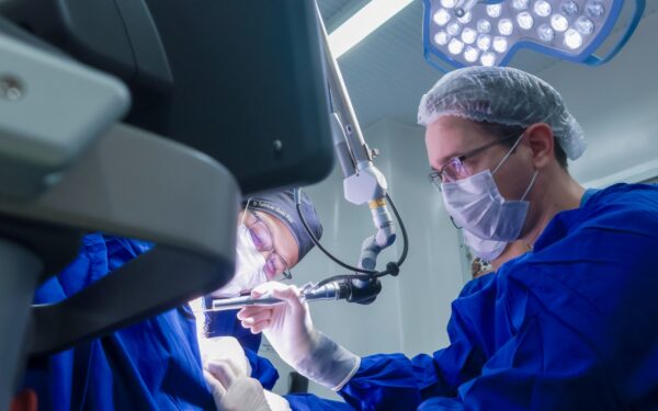 Cirurgiões realizando procedimento com microscópio cirúrgico